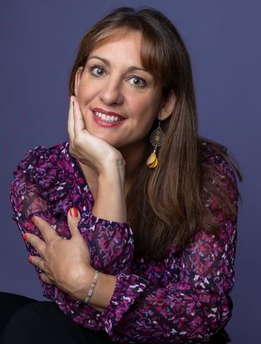 Caroline Thibault Astrothe, astrologue grande, brune, souriante avec un chemisier à fleurs violet 