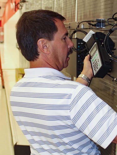 A professional network technician uses a handheld testing device to certify voice and data connections