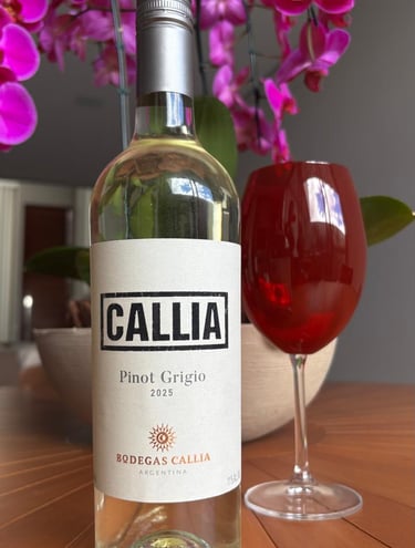 Uma garrafa de vinho branco Pinot Grigio da Bodegas Callia ao lado de uma taça de vinho tinto