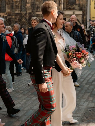 a man and woman in plaidered kilts walking down a street