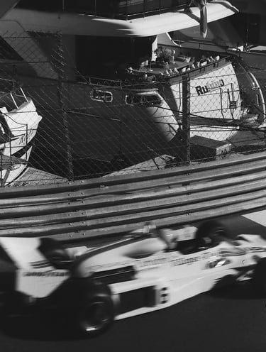 a race car racing down the track with a boat in the background in Monaco