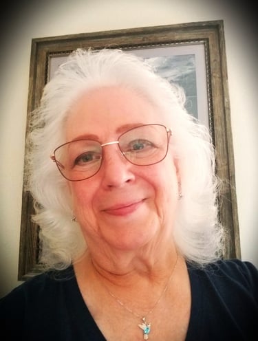 a lady with glasses and a bird necklace on.