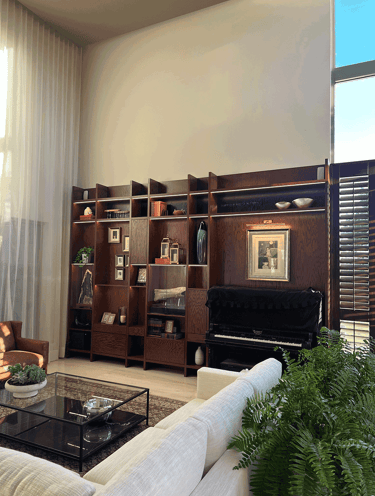 Estantería decorada en sala con piano y luz natural | KARÄNA