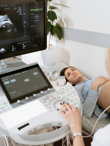 A pregnant patient receiving an ultrasound, image focuses on the ultrasound cart 