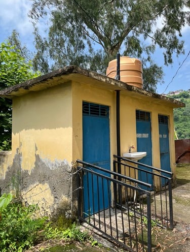 Small yellow toilet block with 3 blue doors.