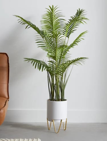 Large faux areca palm tree in a white cylinder pot with gold hairpin legs.