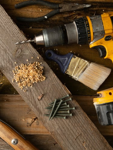 une perceuse avec des outils sur du  bois symbolisant la réparation