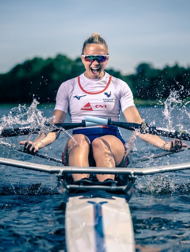 Sport portrait of an athlete rowing a single scull on the water, facing forward.