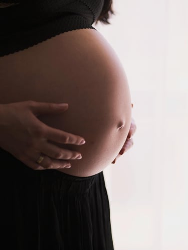 a bare pregnant belly of a woman wearing black pants