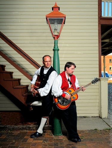 two men hold guitars near a lightest