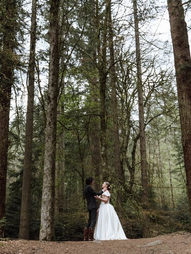 a bride and groom standing in a forest