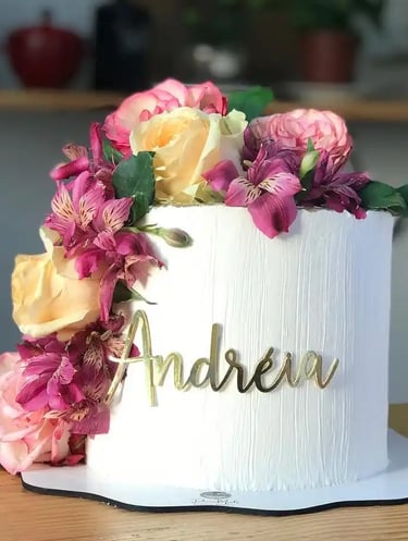 Bolo decorado com flores coloridas e nome "Andreia" em destaque. Ideal para festas e celebrações.