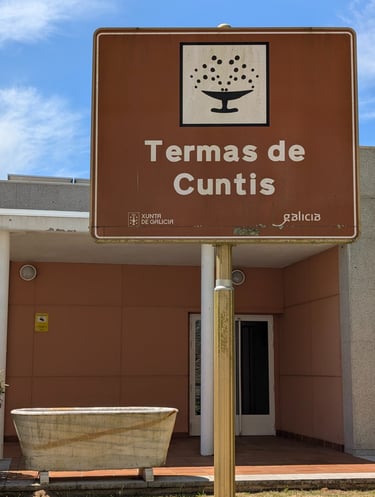 a sign that says Termas de Cunits with a marble bathtub next to it