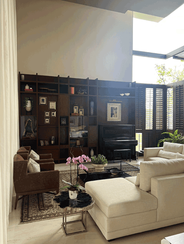 Sala elegante con estantería de madera y piano vertical al fondo | KARÄNA