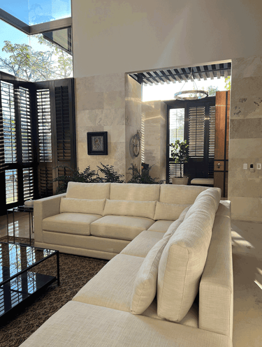 Sala iluminada con sofá esquinero y vista a la entrada | KARÄNA