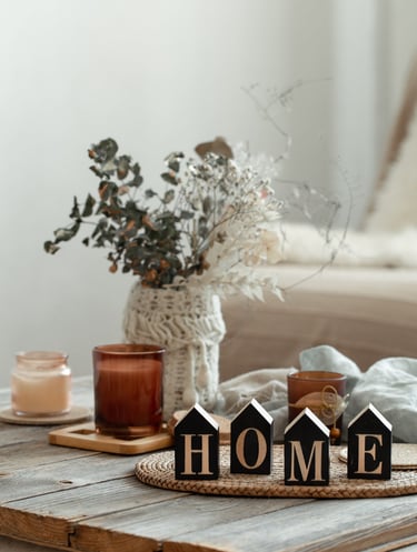Cozy home decor setup with candles, dried flowers, and wooden 'HOME' blocks on a rustic table