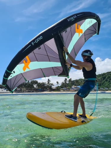 a man is holding a wing on a beginner foil board in the water, in a crystal clear lagoon