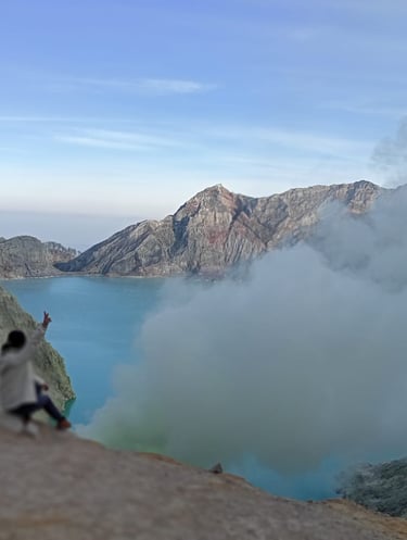 a person sitting on a rock with a view of a lake