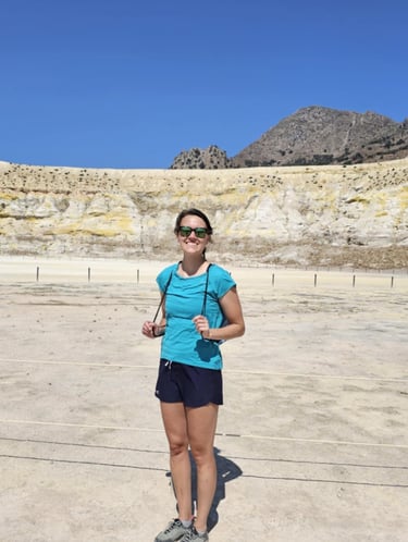 a woman in a blue shirt and sunglasses standing in a desert
