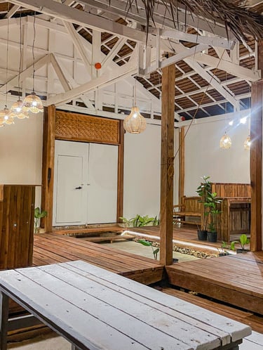 Eco-friendly modern tropical interior with wood decking, woven pendant lights, and exposed rafters.