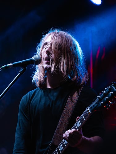 a man with a guitar and microphone in front of a microphone