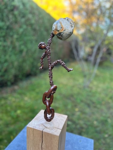 Iron sculpture with stone on wooden pedestal