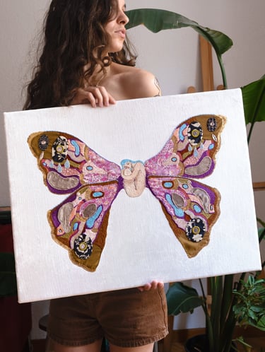 a woman holding an embroidery artwork of a butterfly
