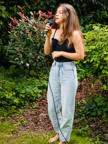 ein Mädchen, das in ein Mikrofon singt - im Garten