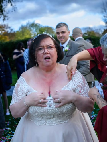 A bride in an off-the-shoulder lace wedding dress adjusting her gown at an outdoor wedding reception.
