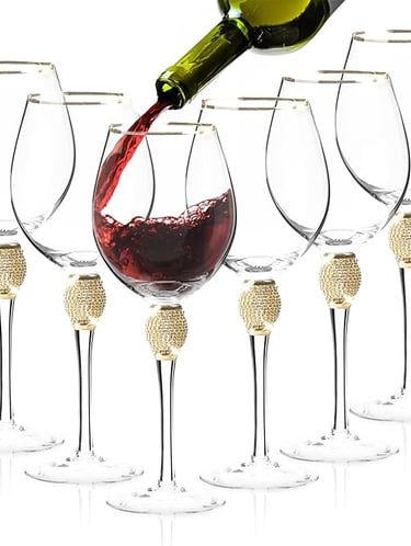 Red wine being poured into gold-stem wine glasses, elegant luxury glassware set.