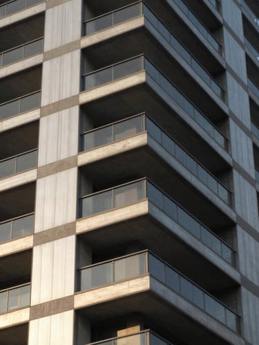 Architectural close-up of premium residential tower in Sector 71, showcasing brushed metal panels, structural concrete geometries, and dramatic afternoon sunlight.