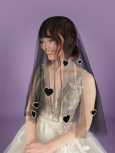 Bride wearing a black wedding veil with velvet hearts on it outlined in pearls
