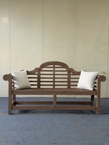 Classic wooden bench with soft cushions, designed as a quiet outdoor seat for relaxed garden living.