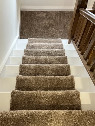 White painted staircase with brown plush carpet runners and a wooden banister railing in Brighton.