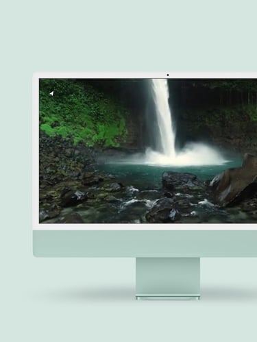 a desktop computer monitor with a waterfall in the background