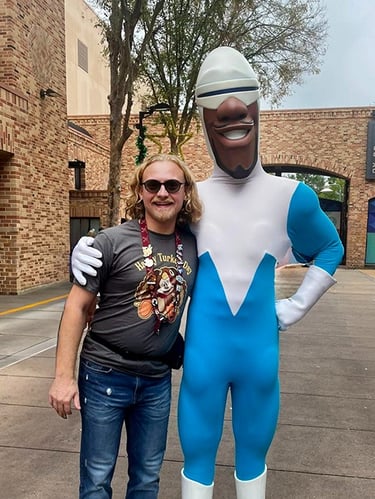 Minnie's Travel Boutique travel advisor Zach Stout pictured with Frozone inside Disney's Hollywood Studios® Park.