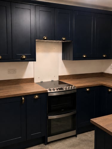 Navy shaker-style kitchen cabinets with brass handles, wood-effect countertops, an electric cooker.