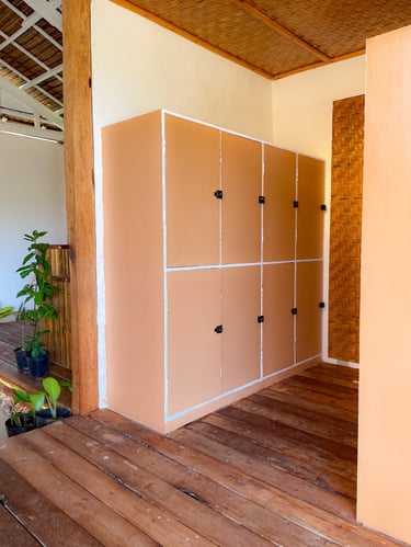 Six-door peach storage lockers on a wooden deck in a tropical building with woven bamboo ceilings.