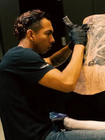 Steven Aguirre, tatuador en Valencia, realizando un tatuaje profesional a un cliente en su estudio