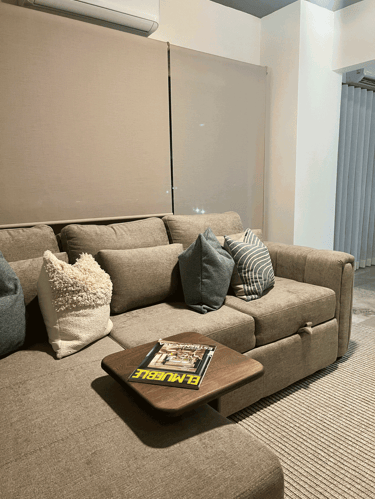 Sala con sofá seccional en tonos tierra, cojines decorativos y mesa auxiliar de madera | KARÄNA
