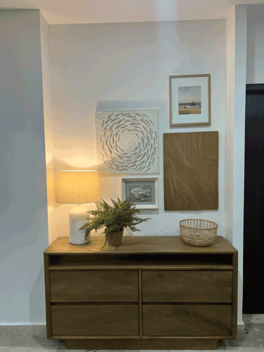 Mueble de recibidor con lámpara cálida, plantas y galería de arte mural en tonos neutros | KARÄNA