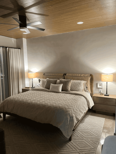 Recámara con techo de madera, cama king size y lámparas de mesa sobre burós simétricos | KARÄNA