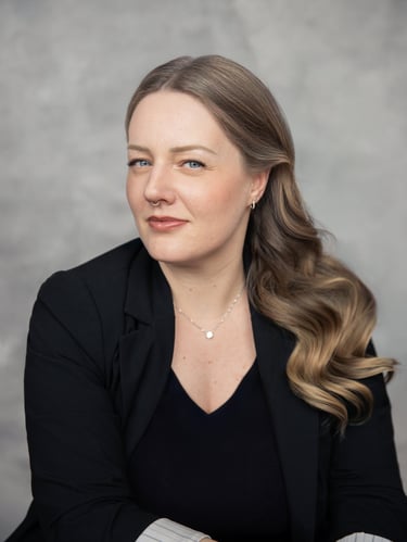 Professional corporate headshot of a woman with blonde wavy hair wearing a black blazer.