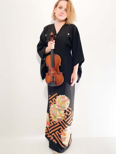 Violinist Zydre in a black kimono-style dress holding a violin, contemporary classical artist portrait