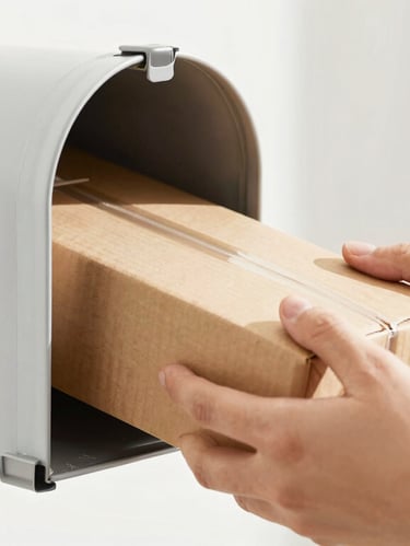 Close-up of a hand securely retrieving a package from a clean private mailbox, bright natural light, 35mm