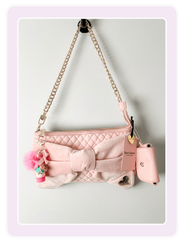 Light pink Juicy Couture quilted shoulder bag with velvet bow and gold chain strap hanging on a wall.