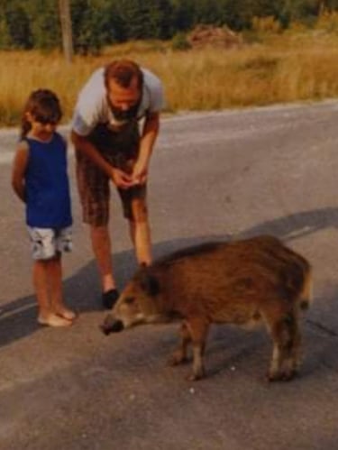 A man and a young child with a wild pig