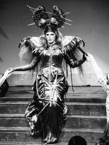 drag queen in oversized spiky hair fixture descends stage steps into audience in long gown