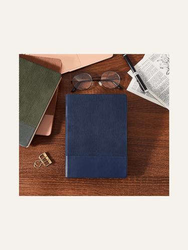 picture of leather-bound journals in dark blue and olive green on a table & showing reading glasses