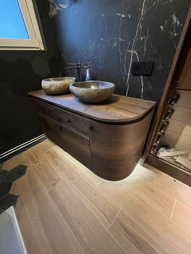 Modern bathroom vanity with double stone vessel sinks, wood cabinet, and black marble wall.